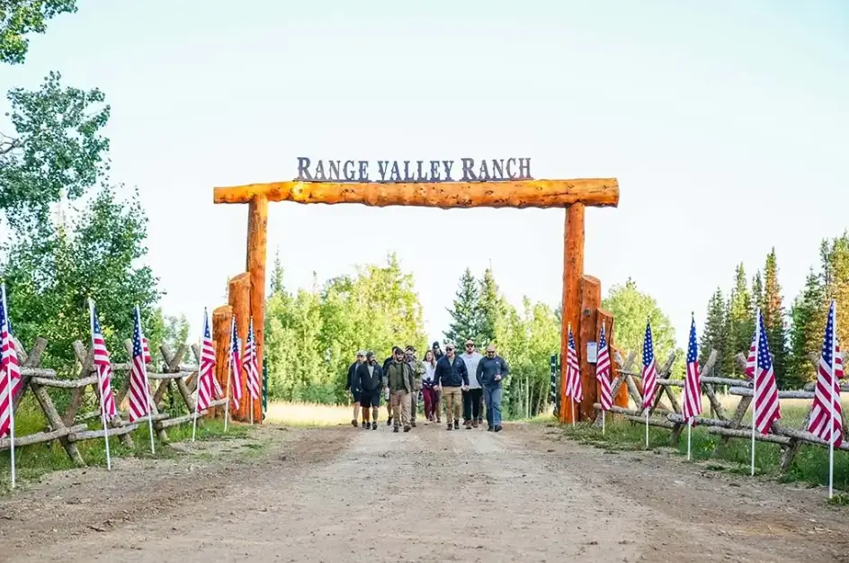 A group of friends positioned at the entrance of a ranch, ready to embark on a shared journey in a picturesque setting.